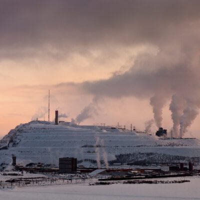 Photo Artwork by Marja Helander. A view of a factory in Kiruna, Sweden, Smoke rises from several chimneys.