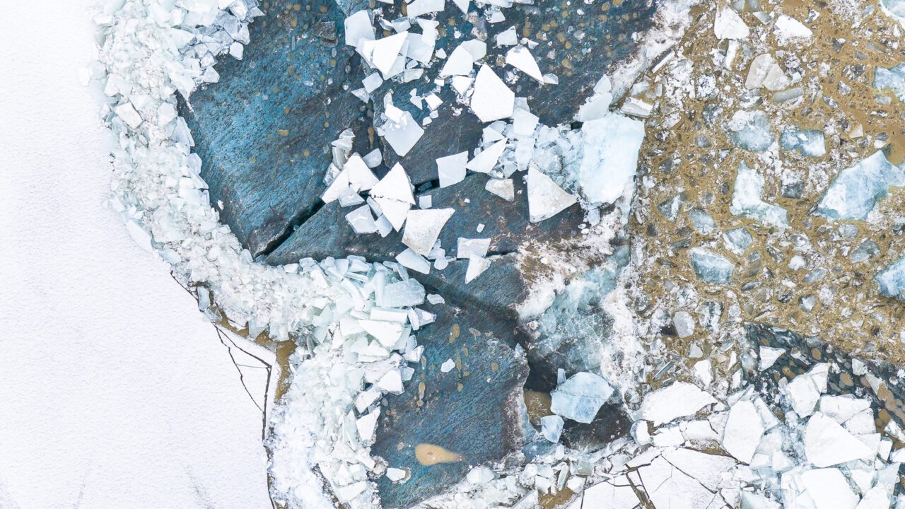 photograph of a glacier, taken from above, white and blue are dominant colours
