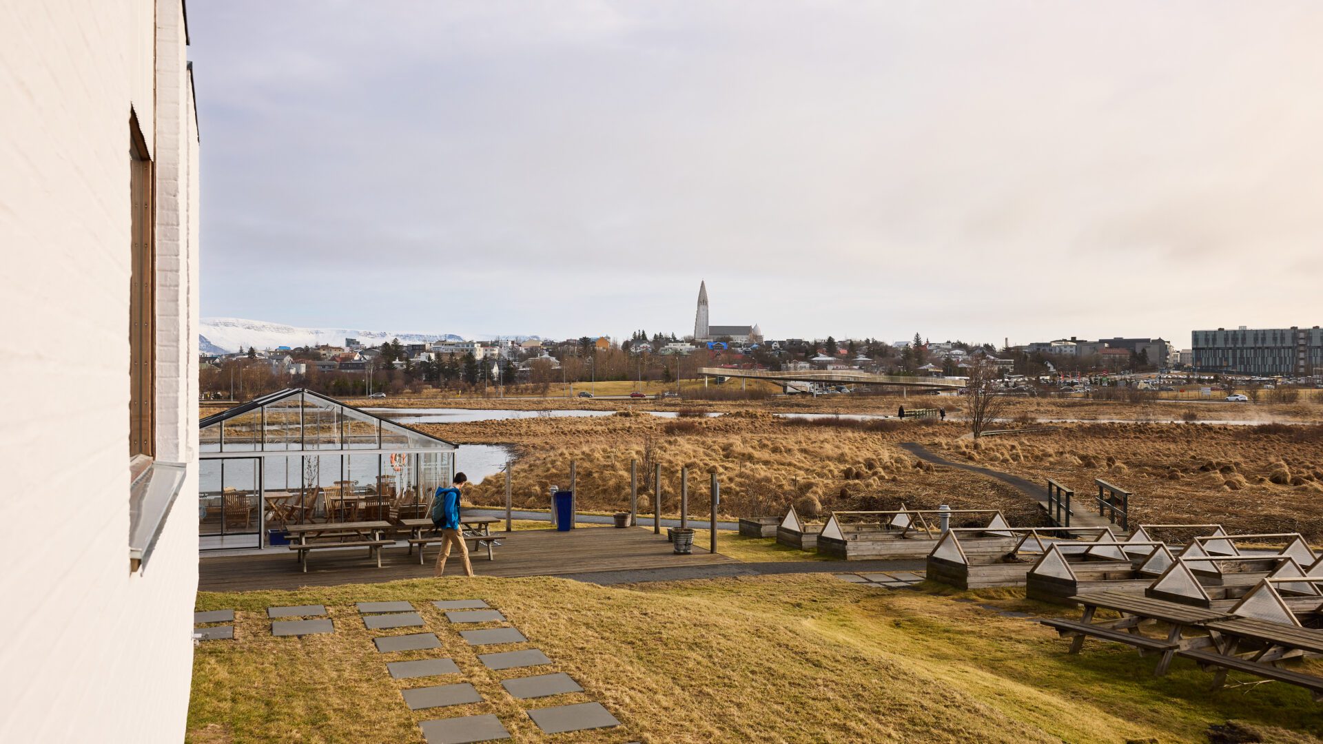 A man walks along a pathway at spring time. In the distance you see Hallgrimskirkja church and the sky. photographer is Jon Gudmundsson.