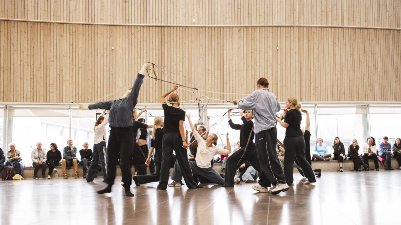 A few people performing a dance infront of sitting people