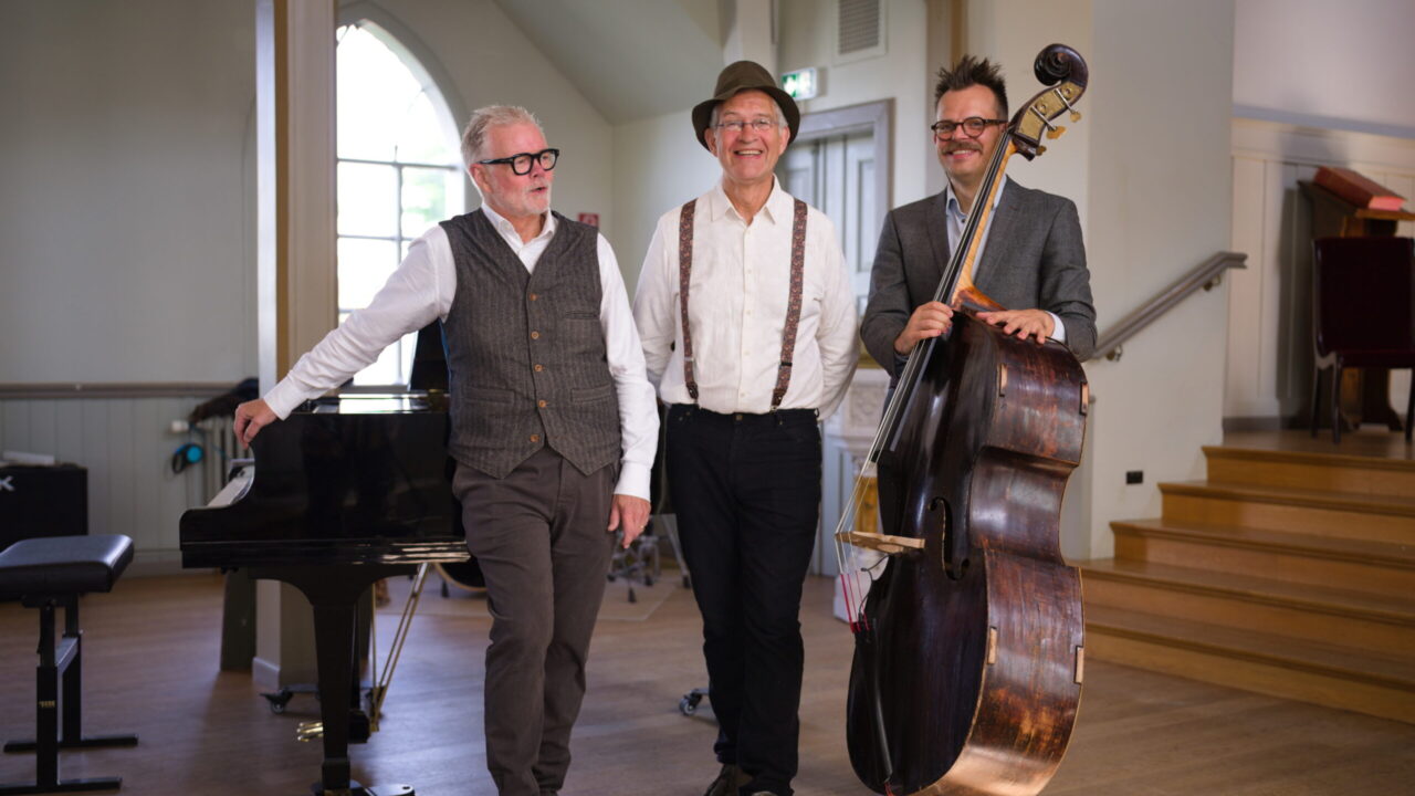 Gunnar Gunnarsson, Aðalsteinn Ásberg Sigurðsson and Birgir Steinn Theódórsson standing by a piano and double bass.