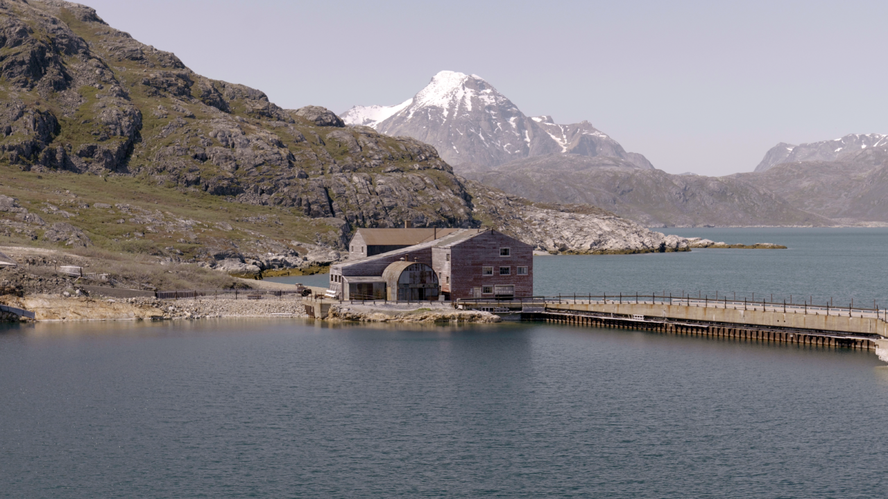 An abandoned building sits by a fjord.