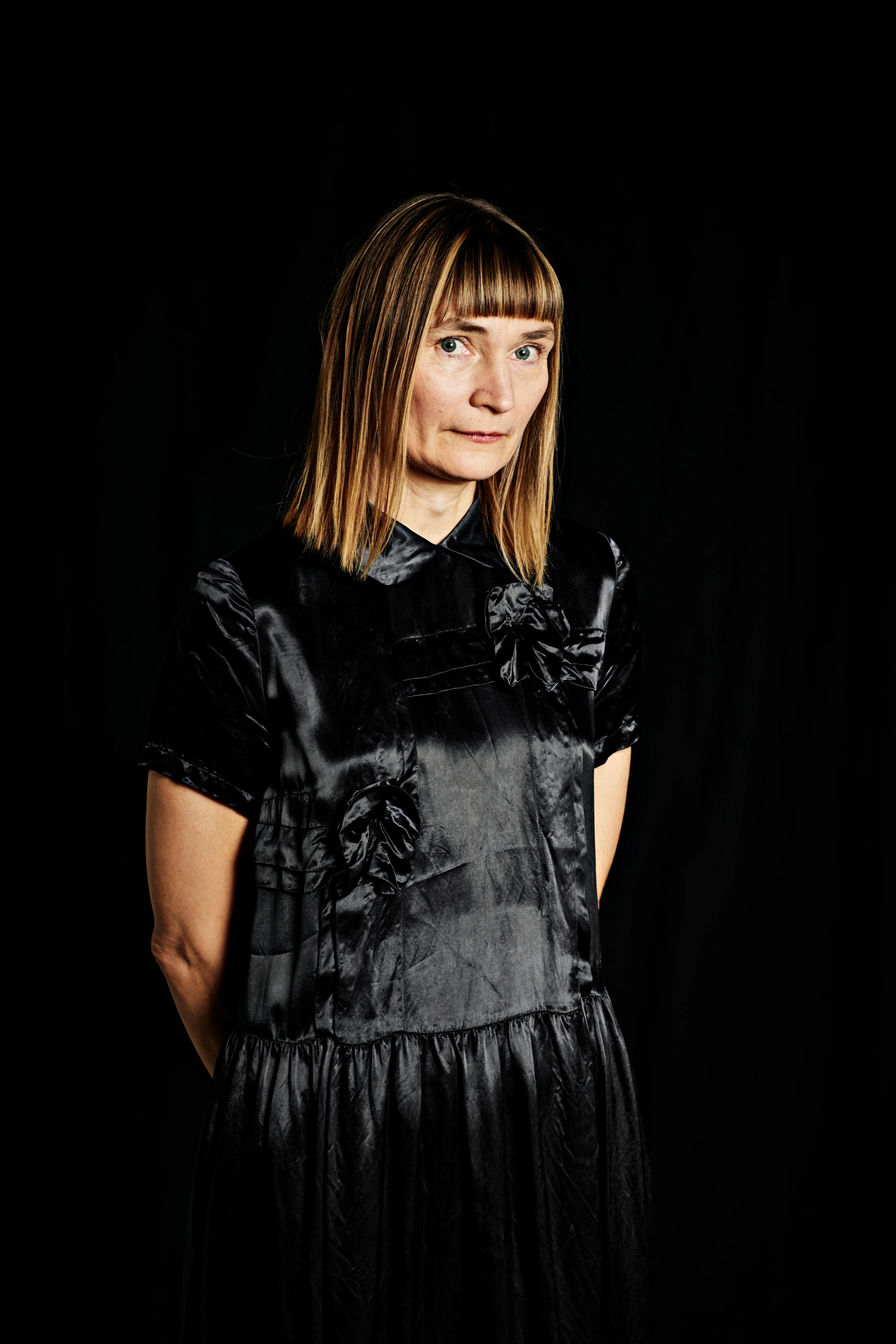 portrait of a woman in black clothes. She has dark blond hair. 